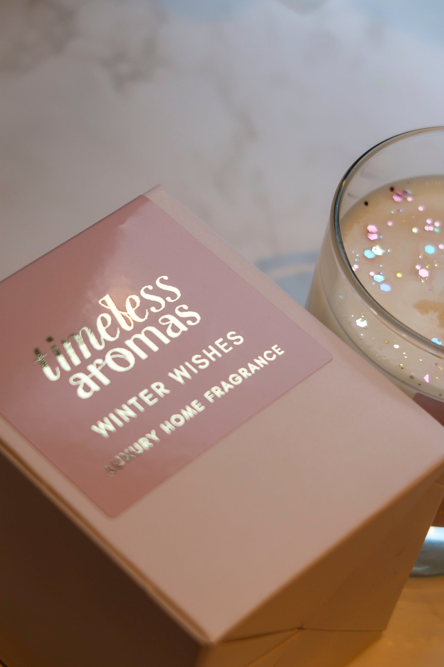 Close-up of Timeless Aromas Winter Wishes luxury scented candle, featuring decorative glitter and the stylish brand label.