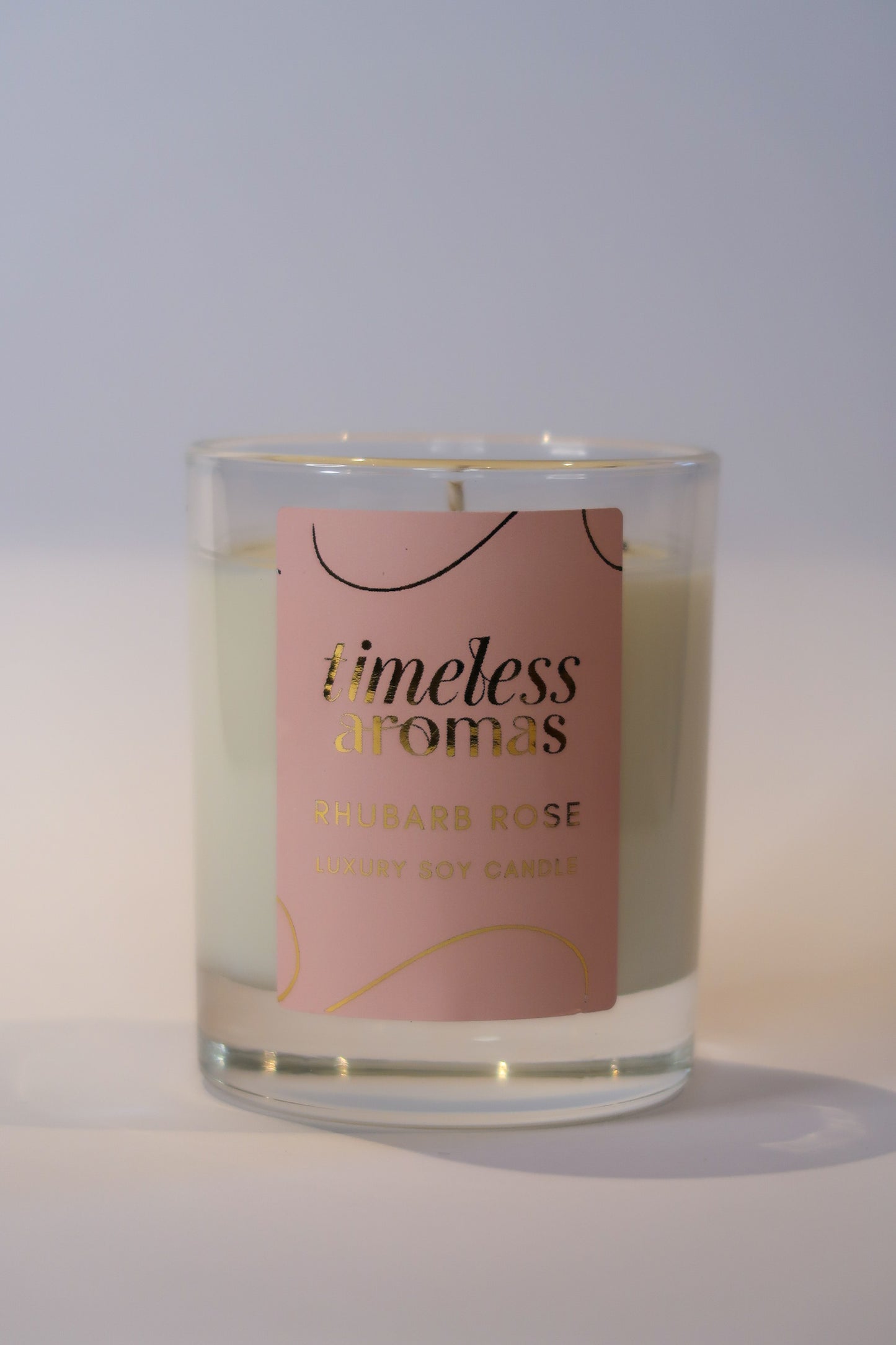 Close-up of Timeless Aromas Rhubarb Rose Luxury Scented Candle, featuring the sleek glass design. The candle embodies the refreshing fragrance of rhubarb rose luxury scented candle.