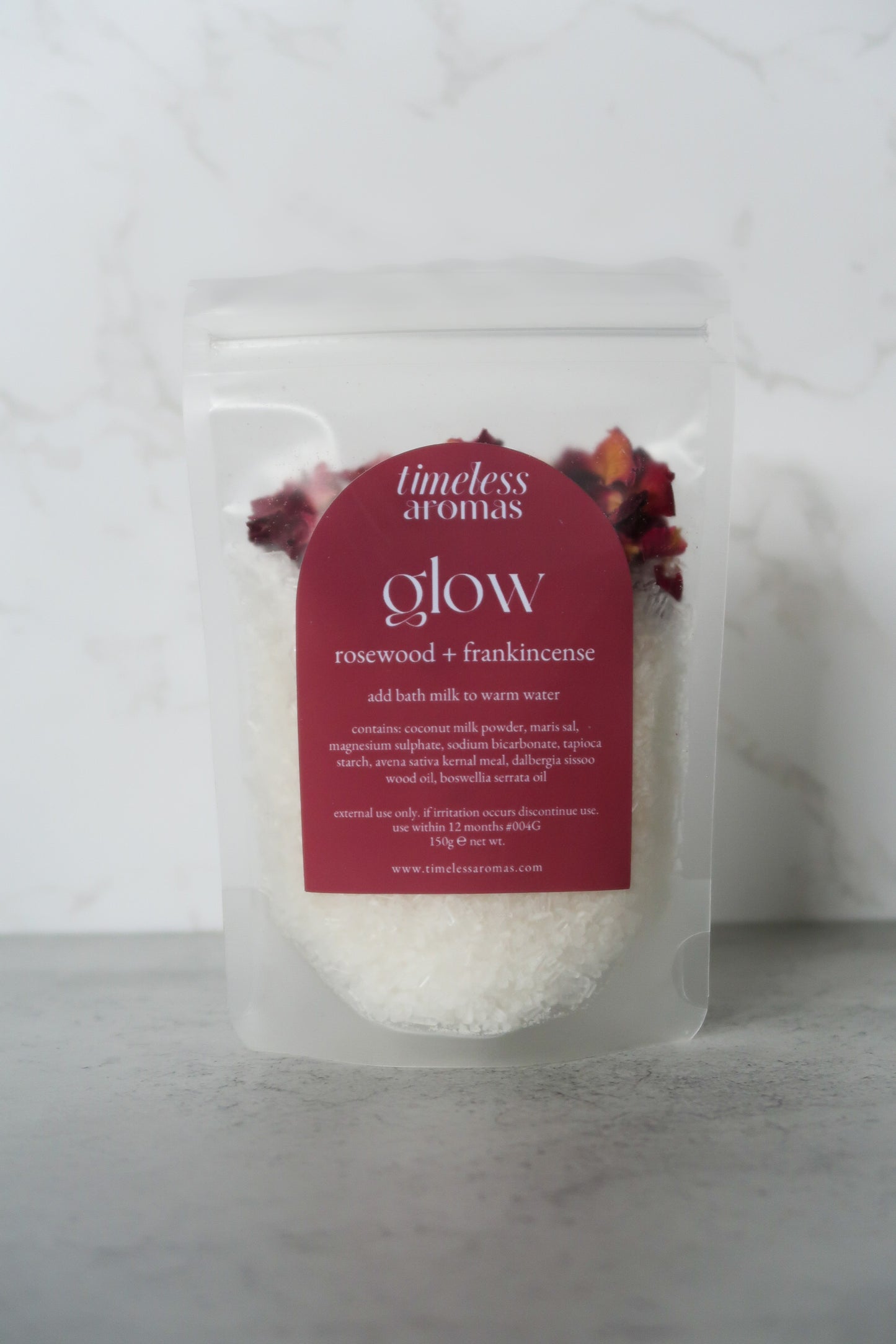 Glow Bath Milk by Timeless Aromas packaged in a clear bag, featuring rosewood and frankincense, with a label that highlights the glow vegan bath milk benefits.