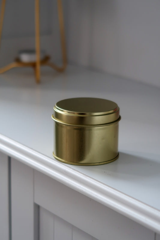 Close up of 100g Gold Tin Candle showcasing the beautiful wax and gold tin design, an exquisite example of hand poured scented candles available in various fragrances. Blank label candles, wholesale candles, white label candles.