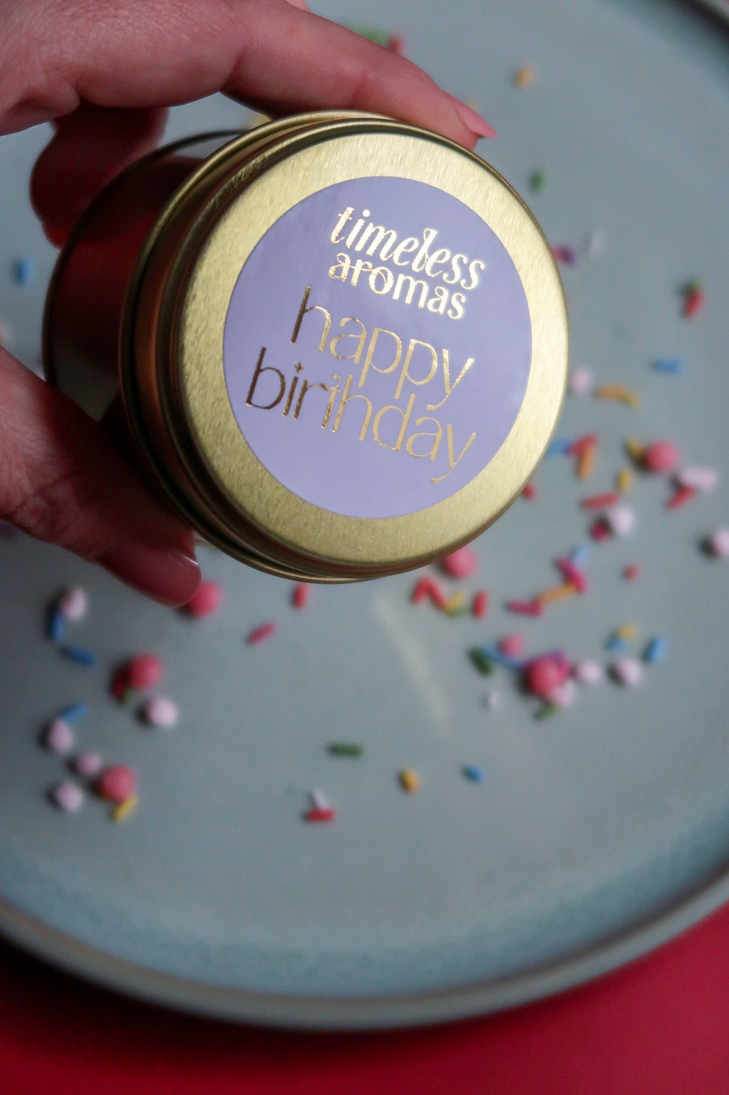 Close-up of the Happy Birthday Travel Tin Candle by Timeless Aromas held in a hand, showcasing its label, ideal as a birthday tin candle gift.