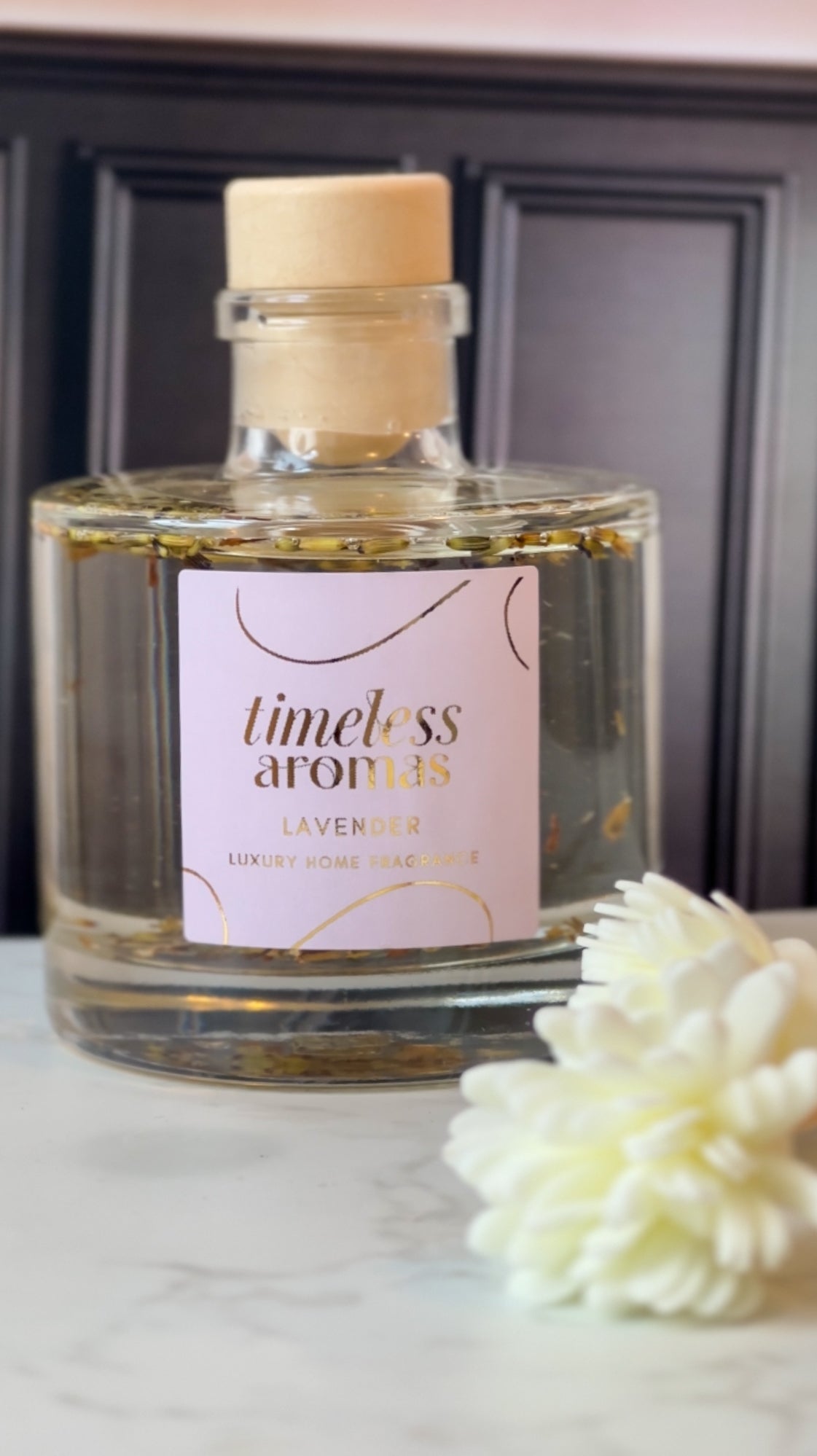 Timeless Aromas' Lavender Luxury Reed Diffuser in a stylish glass bottle with a wooden cap, sitting elegantly on a marble surface, perfect for creating a calming atmosphere.