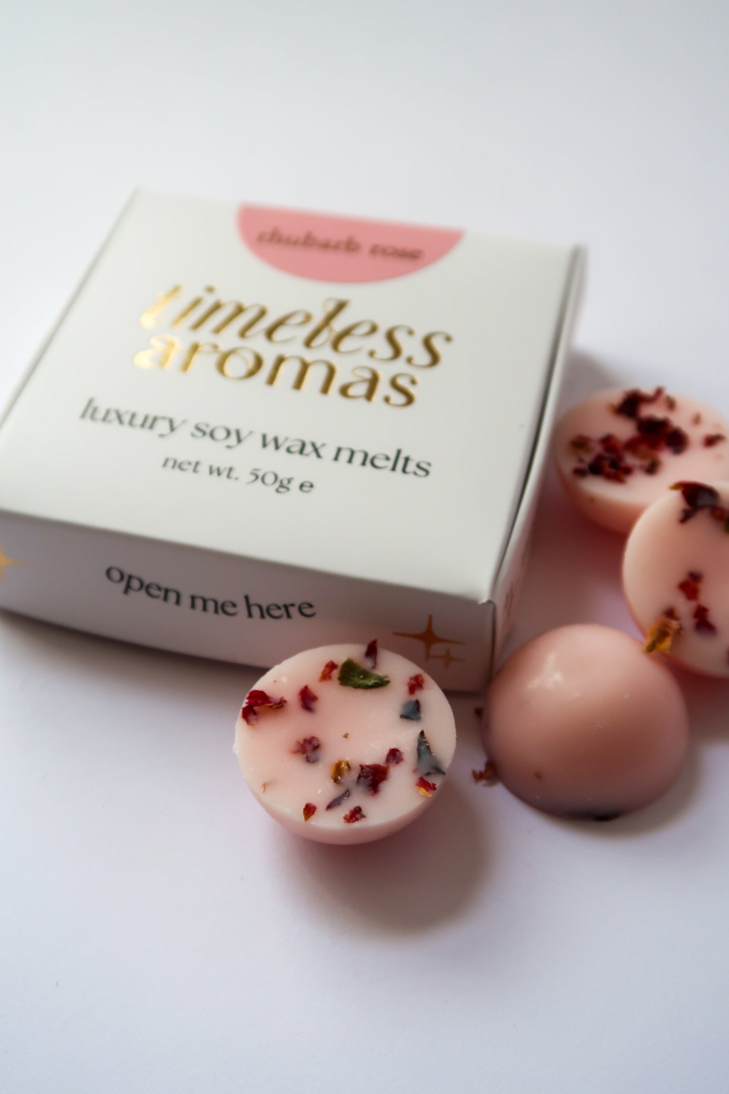 Close-up of Rhubarb Rose Luxury Wax Melts Box by Timeless Aromas with mini dome wax melts, highlighting its elegant packaging and floral details.