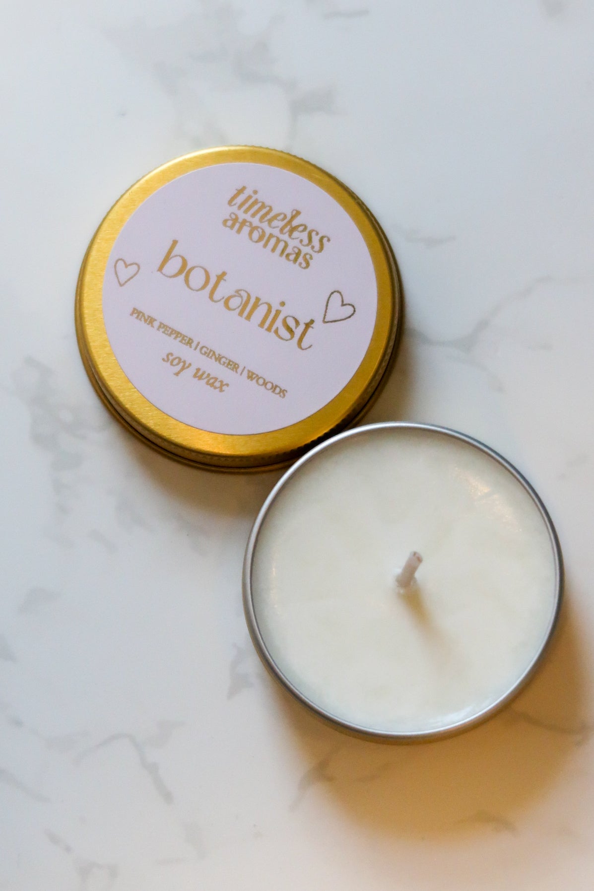 The Botanist Mini Gold Tin Candle by Timeless Aromas Ltd, showcasing a stylish gold screw-top lid with a clean, creamy surface, perfect as a floral and woody mini gold tin candle.