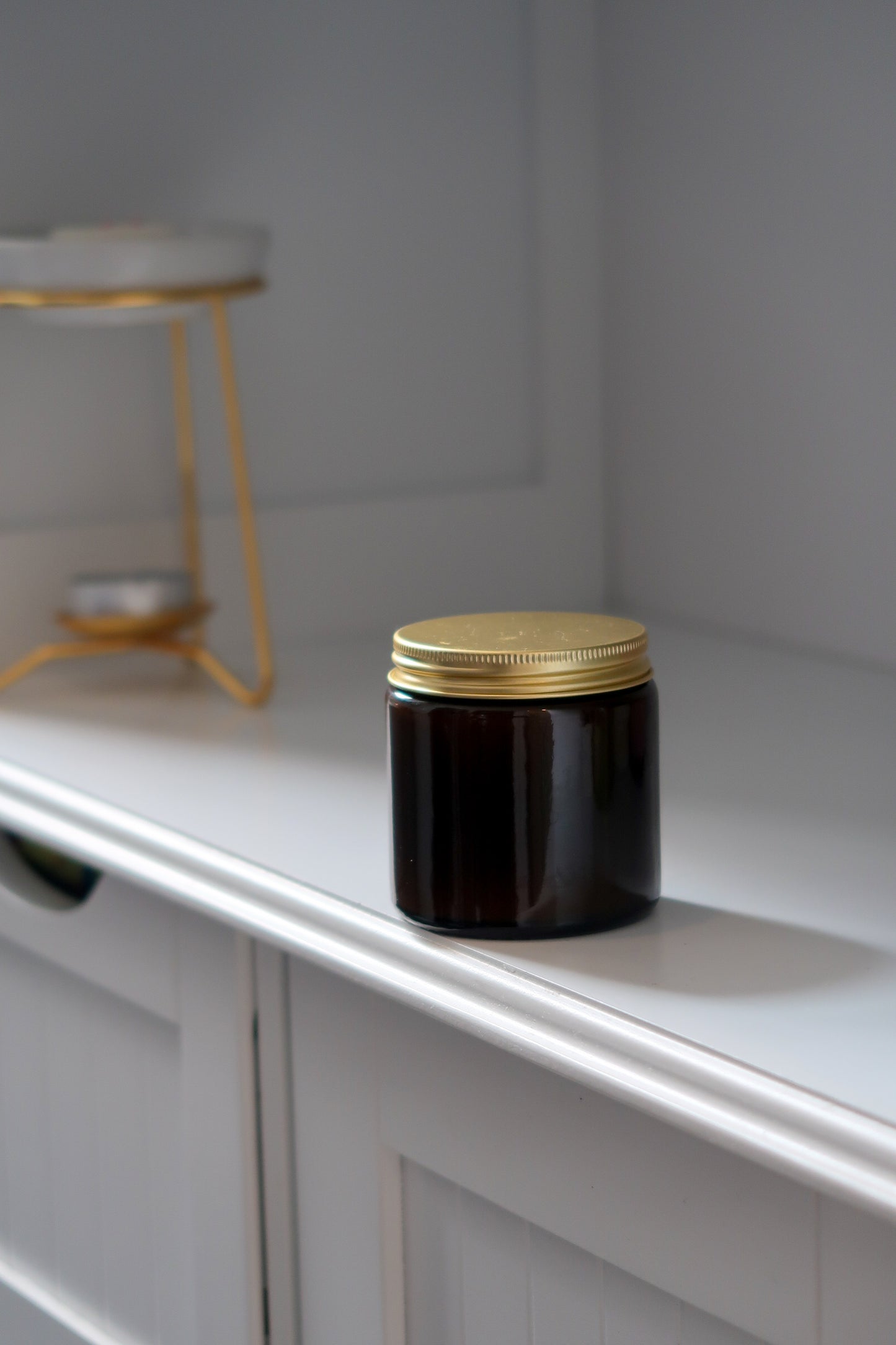 Closed amber glass candle with gold lid from Timeless Aromas Ltd, part of the Amber Glass Candles 120g - Pack of 6. This blank label candle represents hand poured candles, ideal for home fragrance, gifting, or wholesale, presented in a 12cl jar for a sophisticated touch.