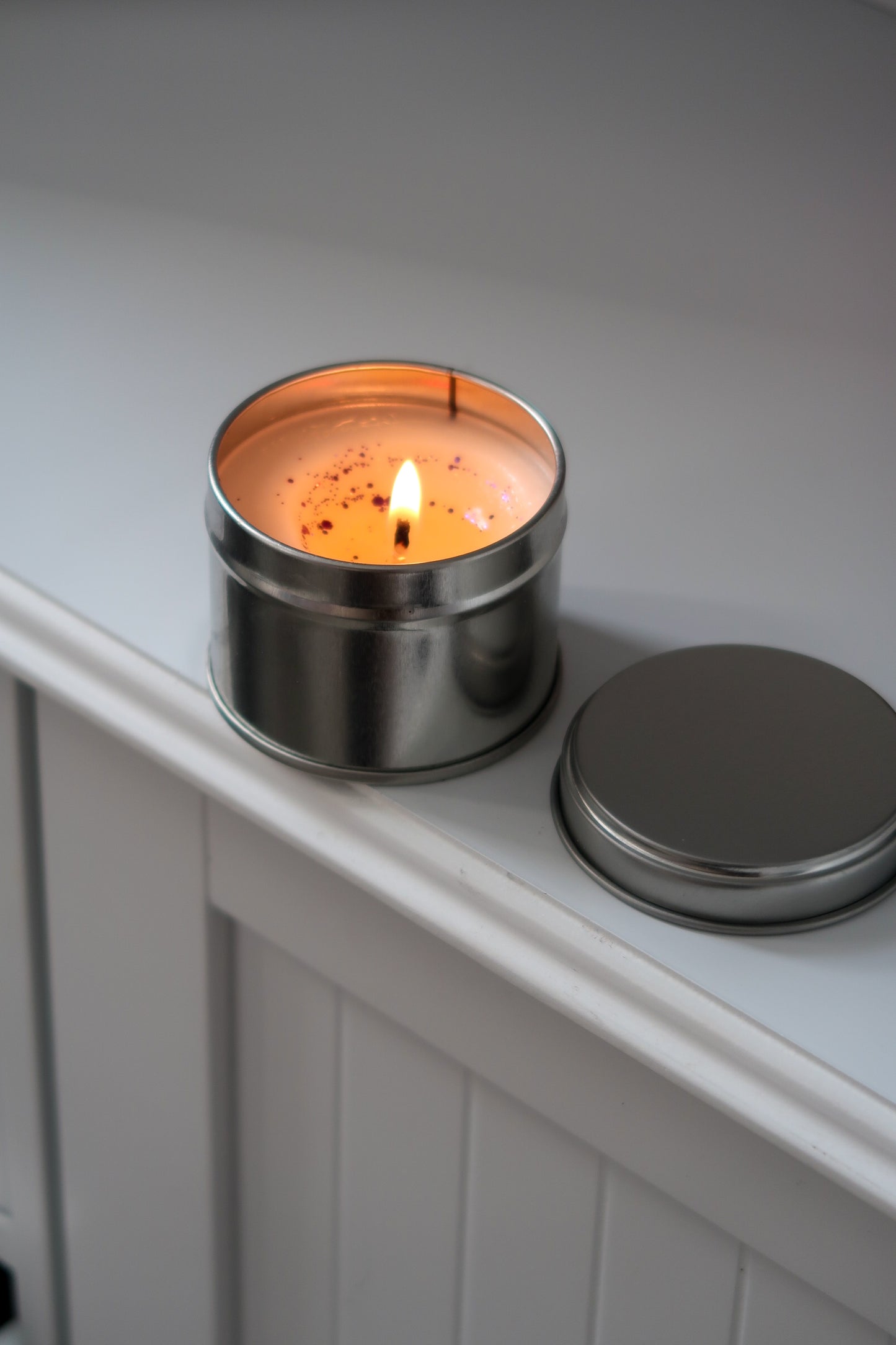 Captivating 100g Silver Tin Candle from Timeless Aromas Ltd, lit and ready to fill your space with fragrance. This hand poured candle, a perfect addition to gift collections, is included in a pack of 6. Ideal for businesses seeking blank candles and white label options.