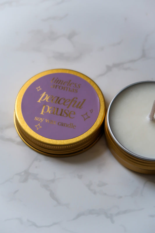 Close-up of the Timeless Aromas Ltd Peaceful Pause Mini Gold Tin Candle featuring a delicate label and the soothing candle's surface.