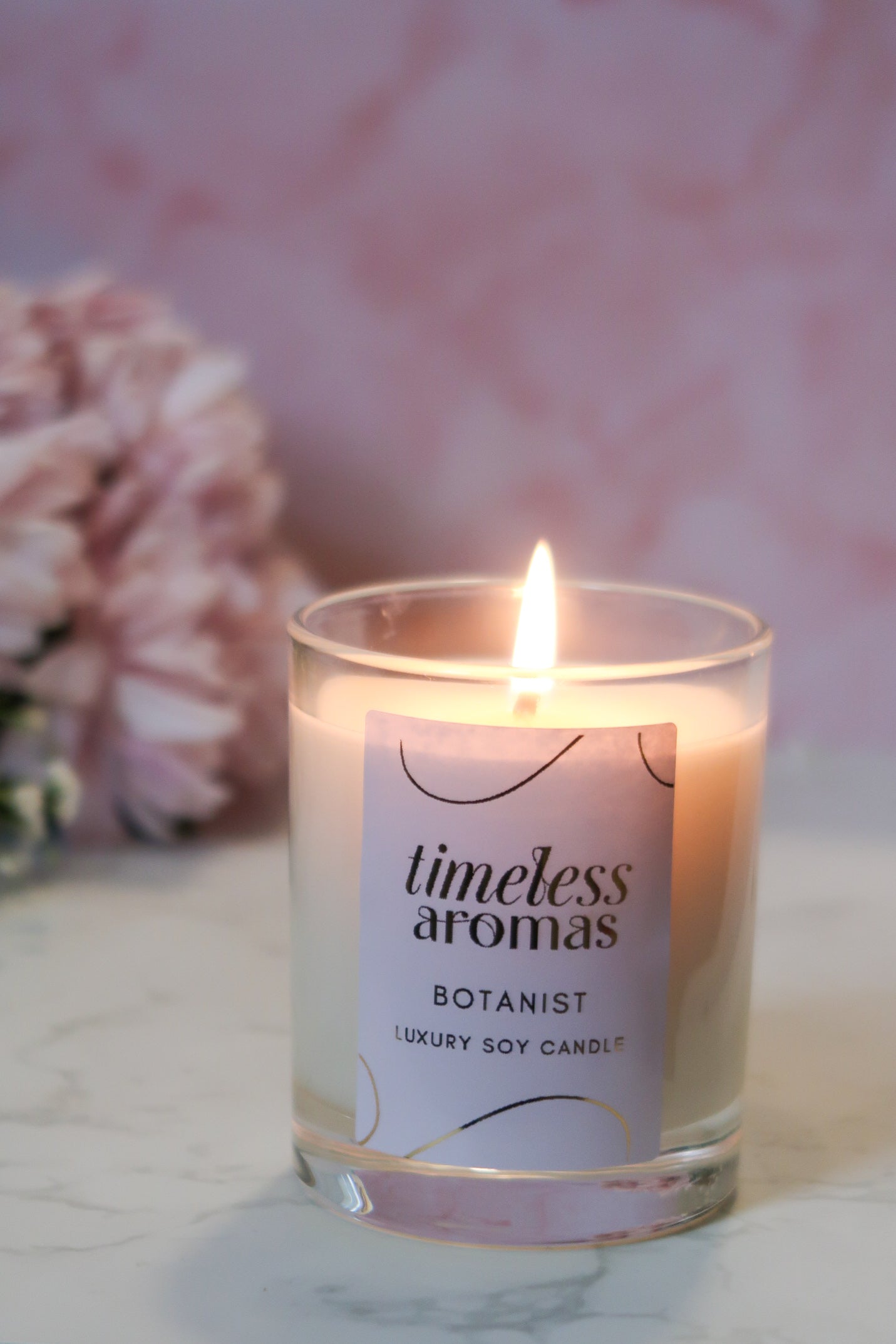 Timeless Aromas Botanist Handcrafted Luxury Candle lit, emitting a warm glow, ideal for creating a relaxing atmosphere.