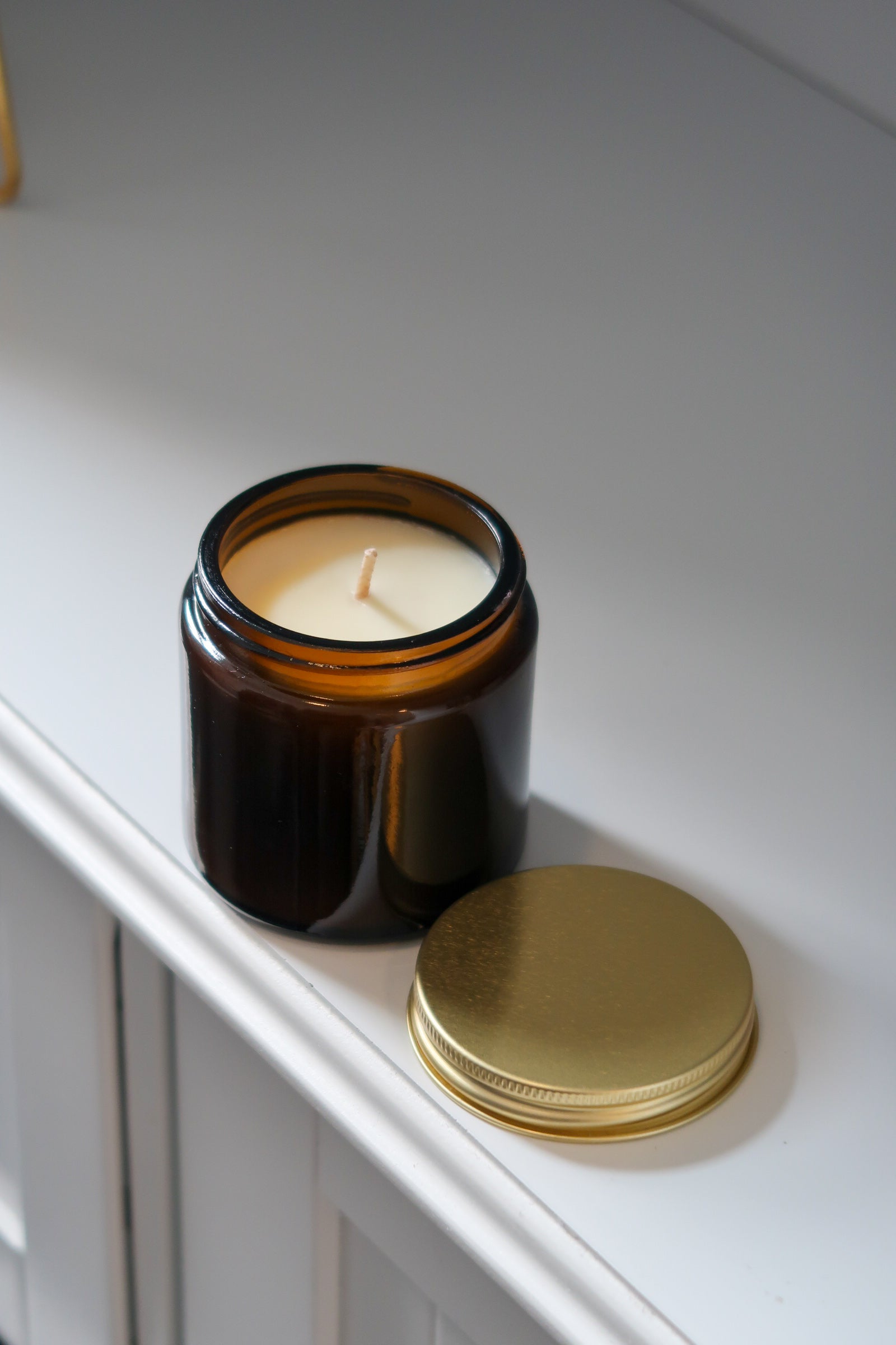 Amber glass candle from Timeless Aromas Ltd showcasing hand poured candles with a gold lid, part of the Amber Glass Candles 120g - Pack of 6. This 12cl jar candle offers beautiful home fragrance and is ideal as a gift or for wholesale, featuring a blank label that can be customized.