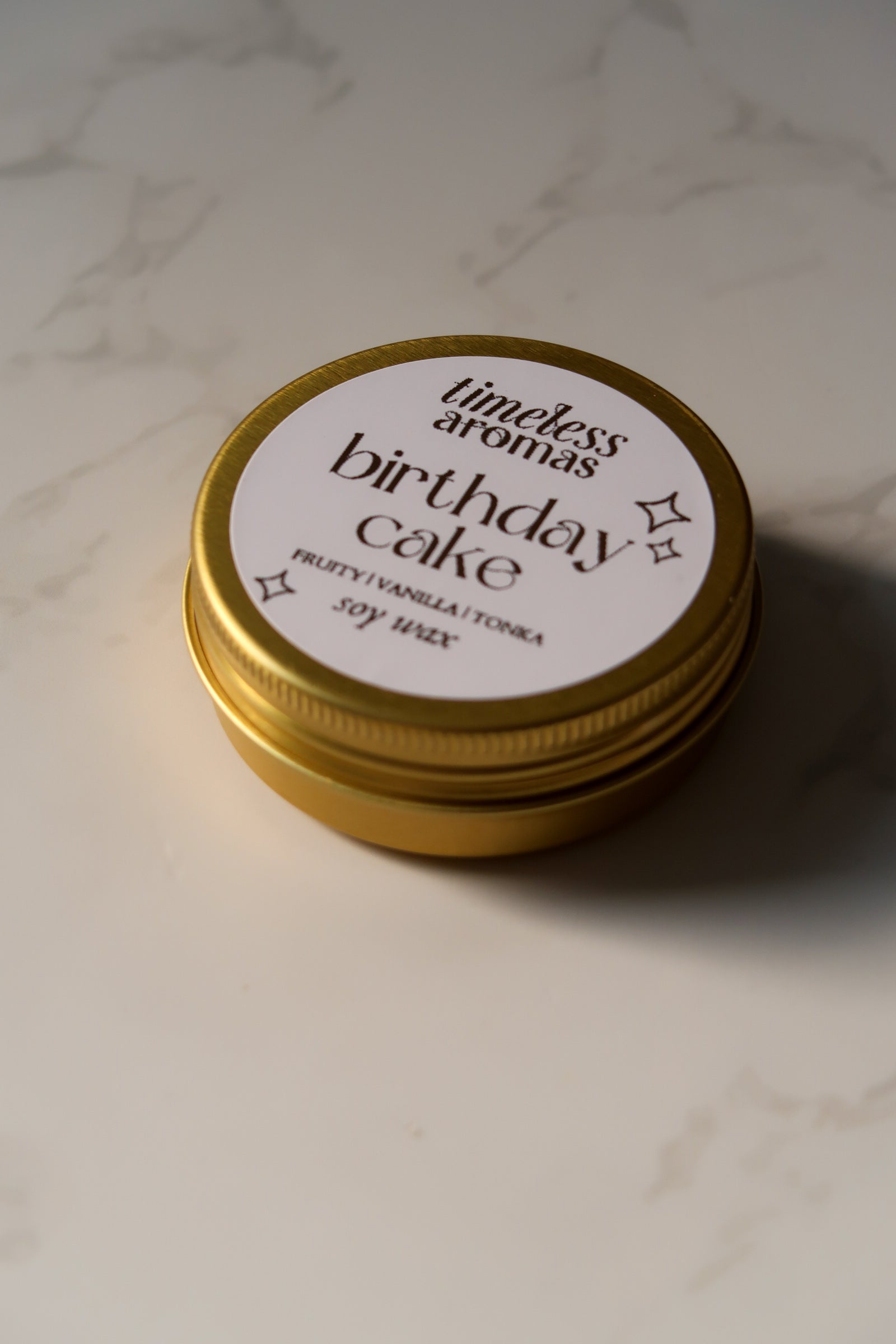 Timeless Aromas Ltd Birthday Cake Mini Gold Tin Candle closed, showcasing its charming gold tin design, perfect for any occasion.