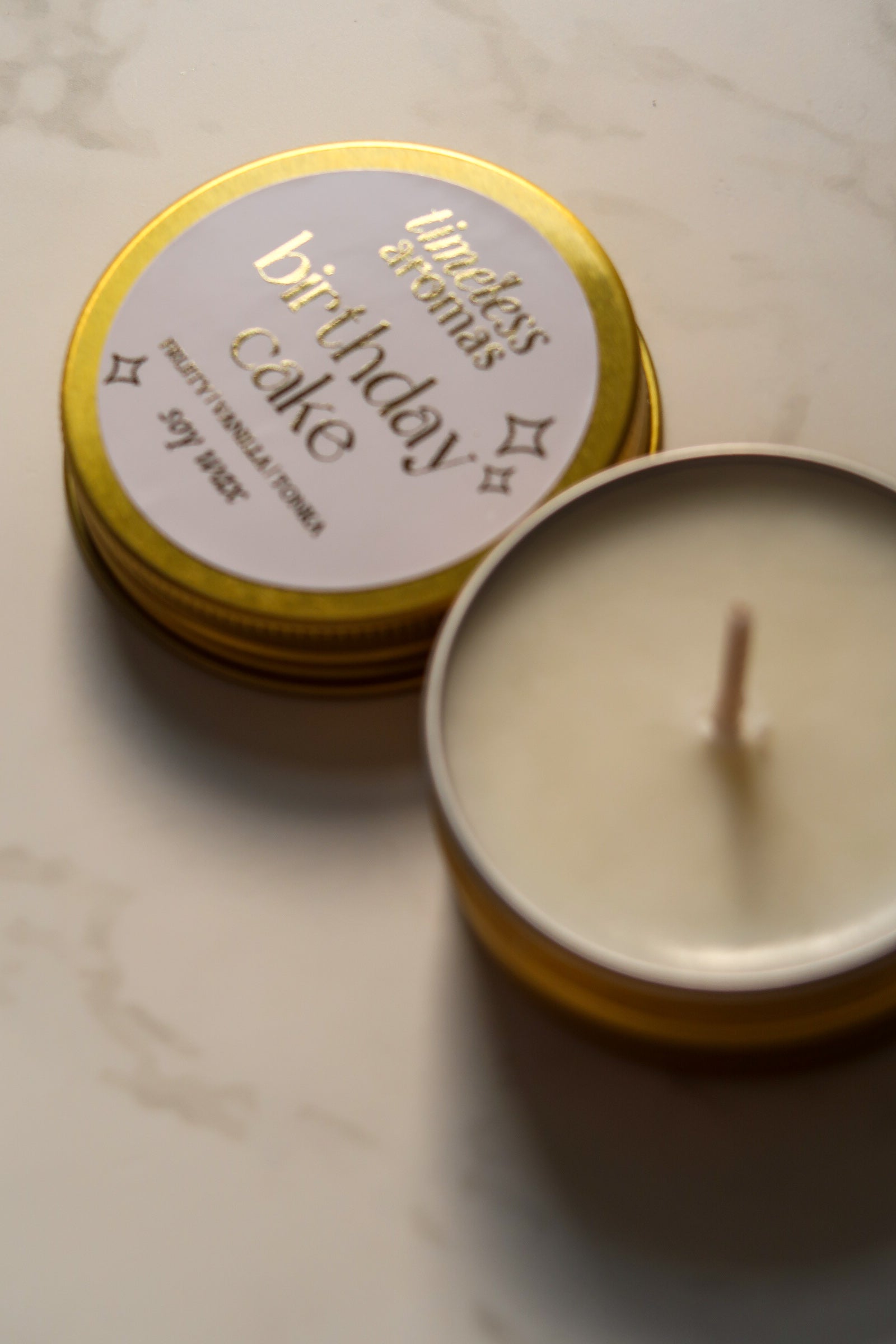 Timeless Aromas Ltd Birthday Cake Mini Gold Tin Candle with lid partially removed, highlighting the high-quality soy wax and inviting fragrance.