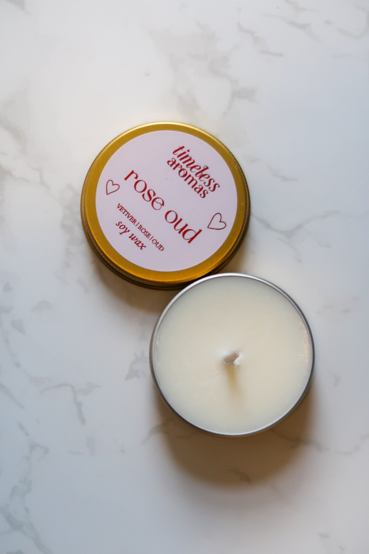 Timeless Aromas Ltd Rose Oud Mini Gold Tin Candle displayed on a marble surface, showcasing its romantic scent and compact design, perfect for travel and intimate settings.
