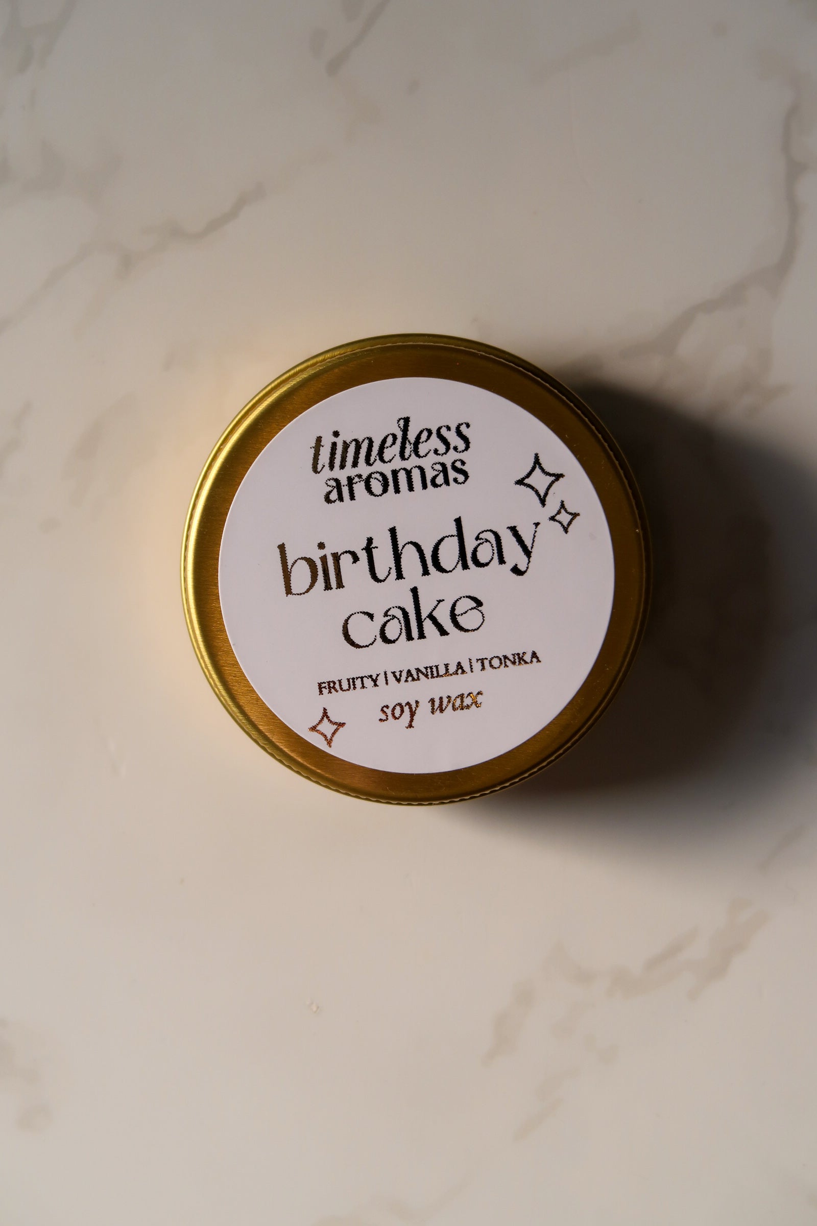 Timeless Aromas Ltd Birthday Cake Mini Gold Tin Candle displaying its elegant gold tin exterior, a delightful addition to any decor.
