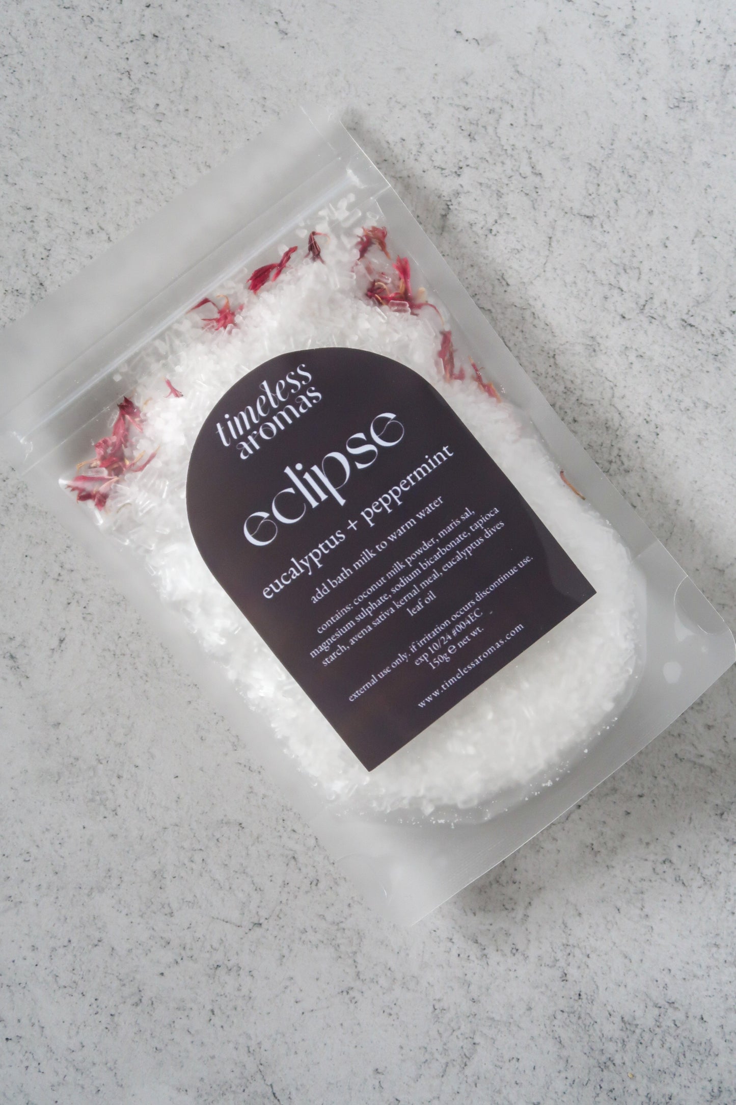 Close-up of Timeless Aromas Eclipse Bath Milk, a vegan bath milk enriched with eucalyptus and peppermint, showcasing the texture of the bath salt and floral sprinkles for a soothing experience.