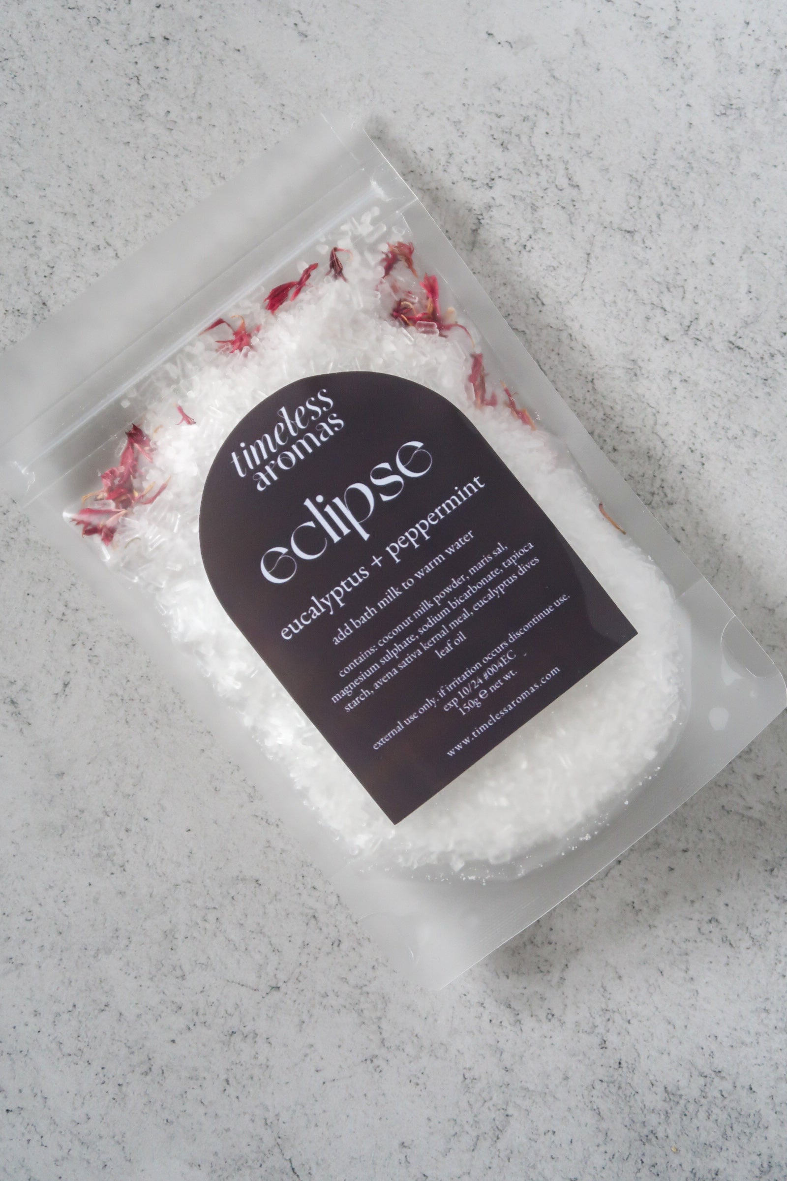 Close-up of Timeless Aromas Eclipse Bath Milk, a vegan bath milk enriched with eucalyptus and peppermint, showcasing the texture of the bath salt and floral sprinkles for a soothing experience.