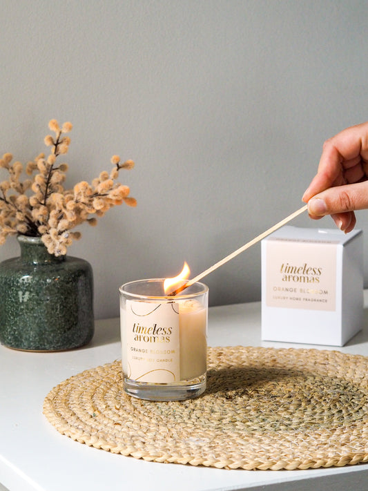 Hand lighting the Orange Blossom Luxury Candle by Timeless Aromas, showcasing its elegant design and warm flame. Perfect for elevating home ambiance.
