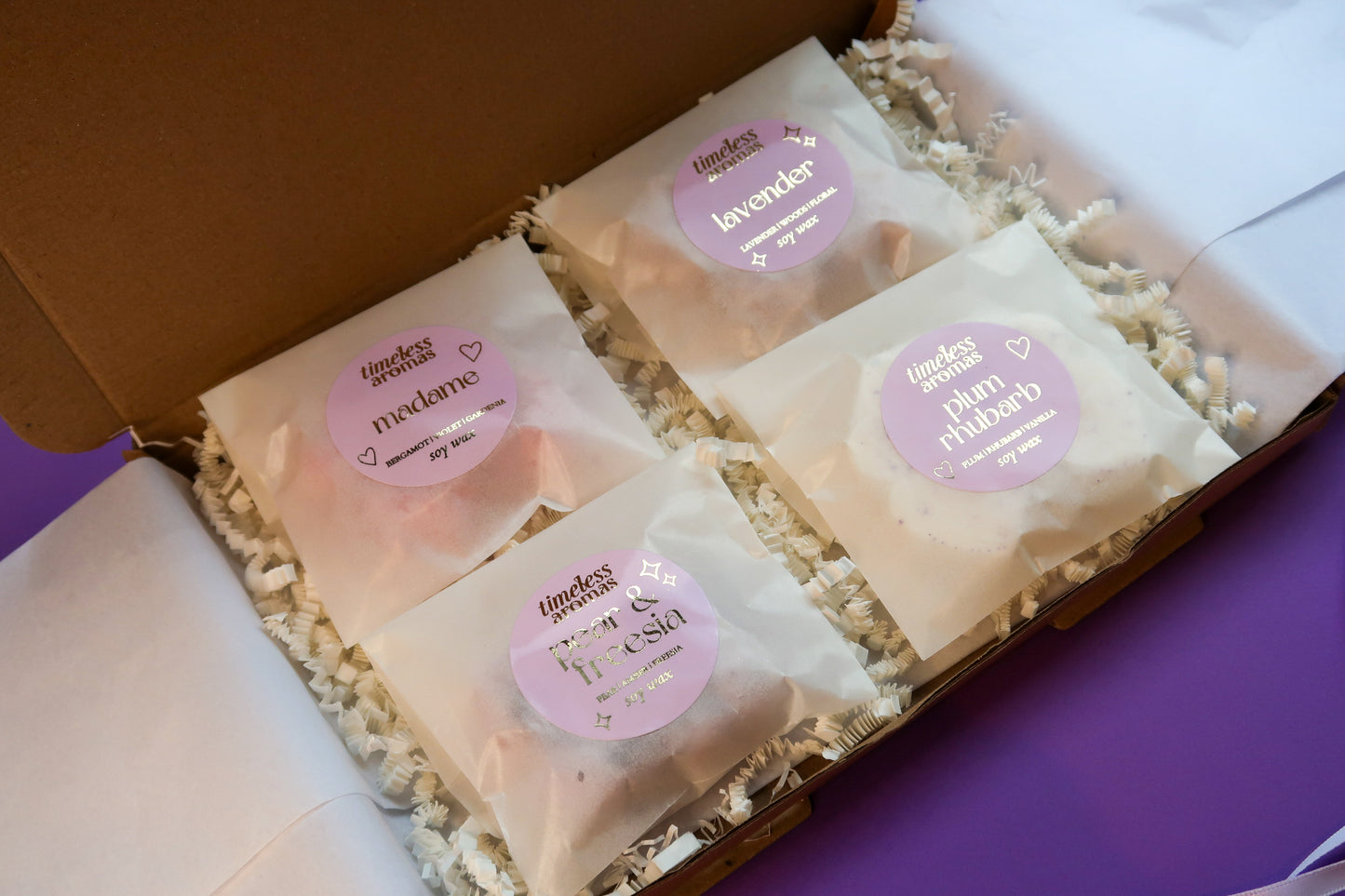 Timeless Aromas Lilac Wax Melt Gift Set displayed with all four wax melts labeled Plum Rhubarb, Lavender, Pear & Freesia, and Madame, perfect for gifting.
