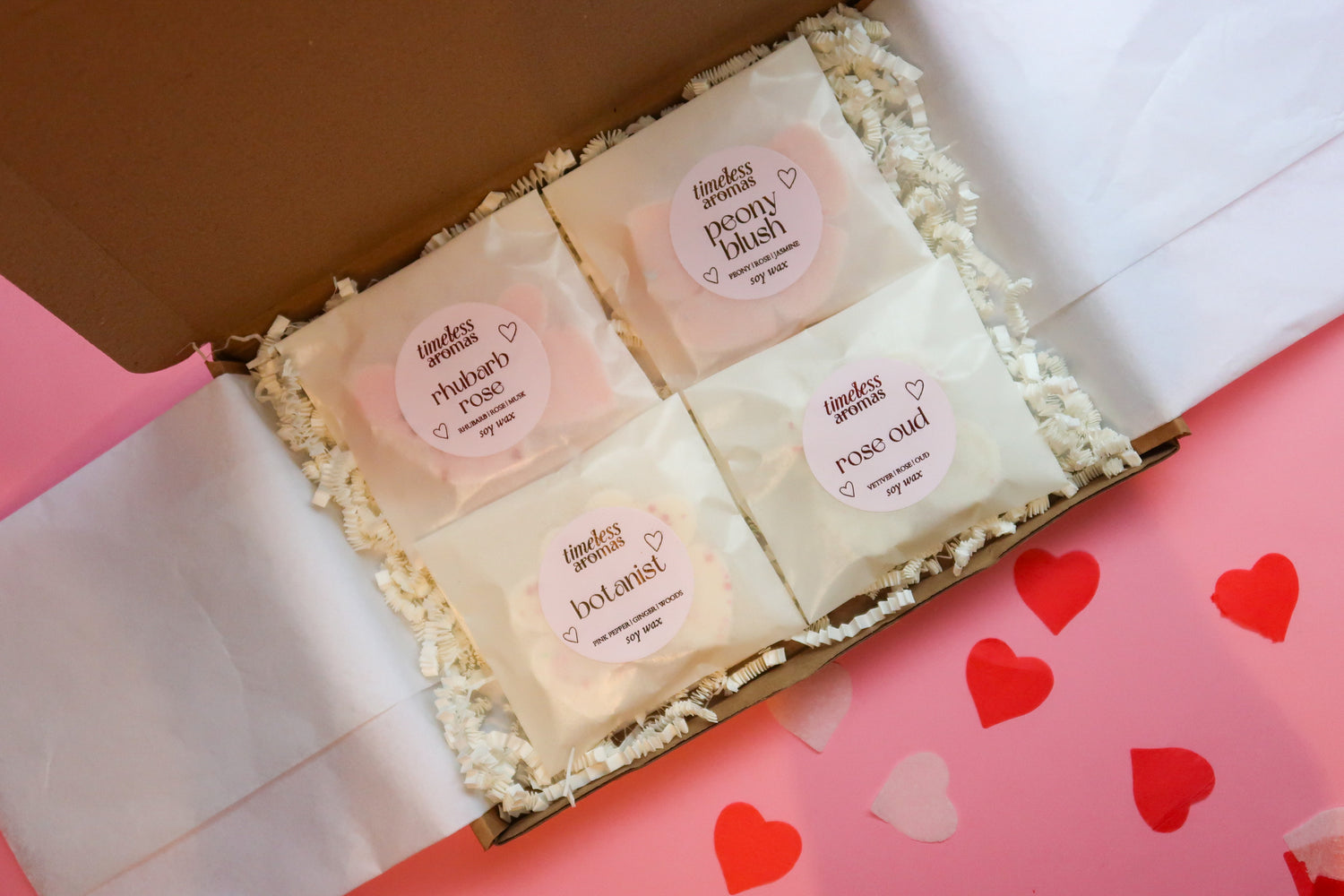 Timeless Aromas Pink Wax Melt Gift Set featuring four beautifully packaged soy wax melts: Rhubarb Rose, Peony Blush, Rose Oud, and Botanist, presented in a charming gift box with decorative filler.