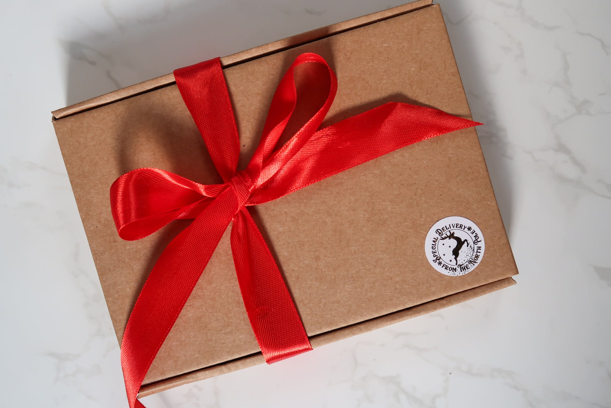 Charming gift box adorned with a red ribbon for the Mini Christmas Candle Gift Set by Timeless Aromas, elegantly presenting four delightful scented gold tin candles.