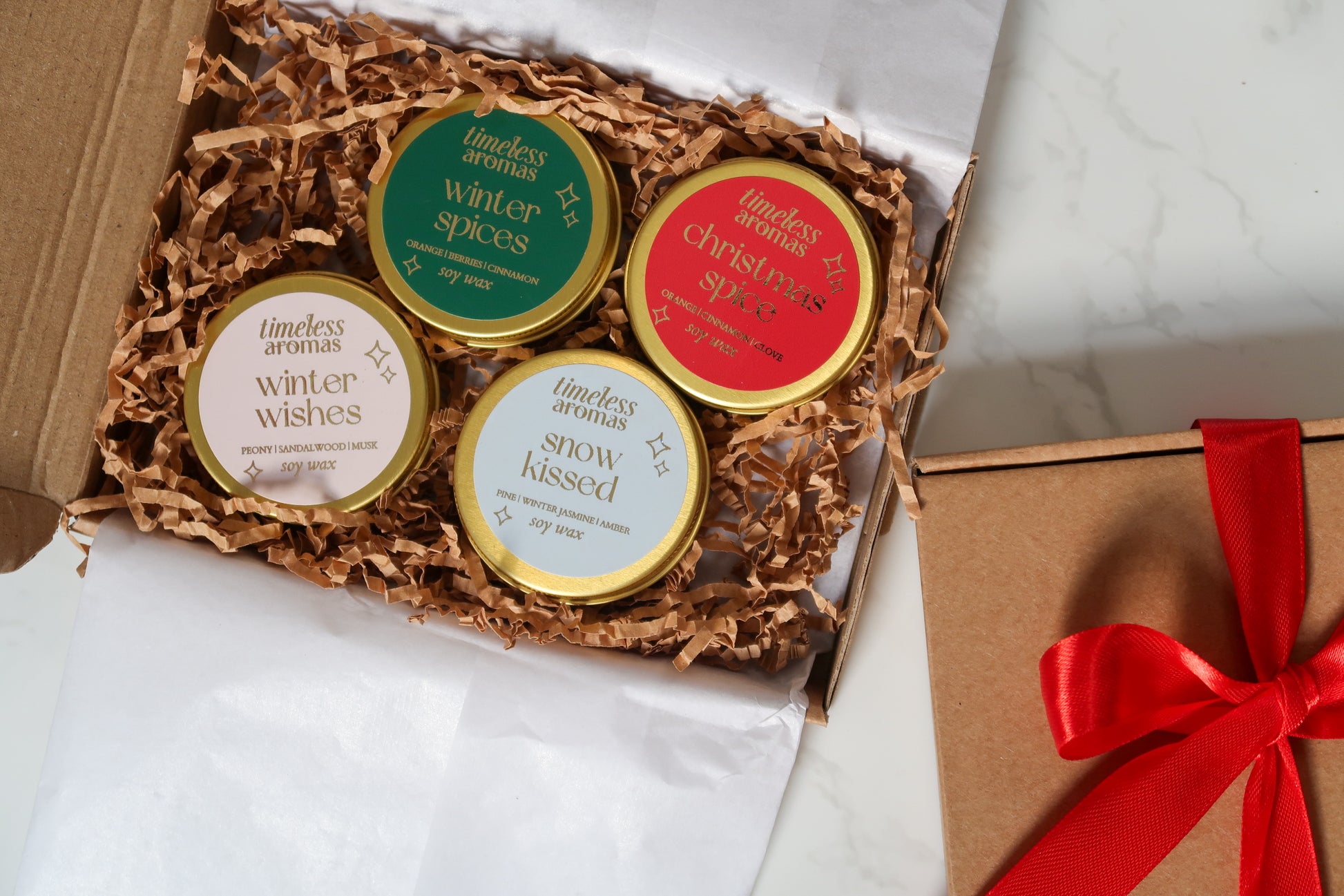 Luxurious Mini Christmas Candle Gift Set by Timeless Aromas featuring four gold tin candles in a beautifully presented box. Includes scents: Christmas Spice, Winter Spices, Snow Kissed, and Winter Wishes.