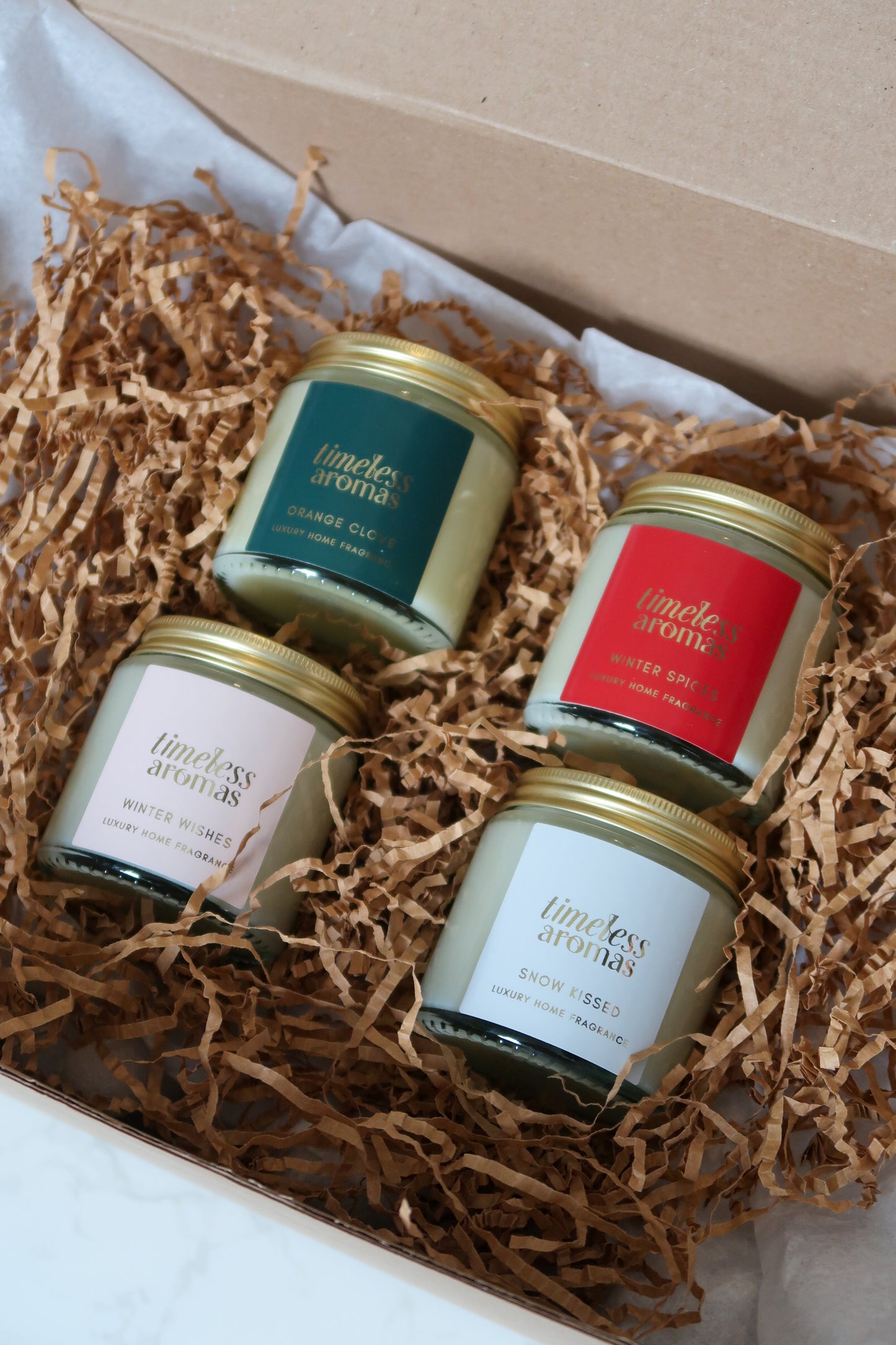 Luxurious Christmas Candle Gift Set by Timeless Aromas Ltd displaying four elegantly packaged gold lidded candles, showcasing scents like Christmas Spice and Winter Wishes, ideal for creating a festive atmosphere with christmas scented candles.