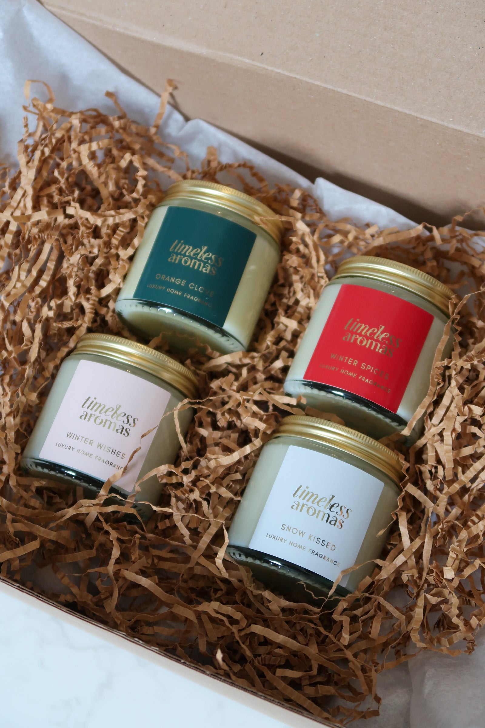 Luxurious Christmas Candle Gift Set by Timeless Aromas Ltd displaying four elegantly packaged gold lidded candles, showcasing scents like Christmas Spice and Winter Wishes, ideal for creating a festive atmosphere with christmas scented candles.