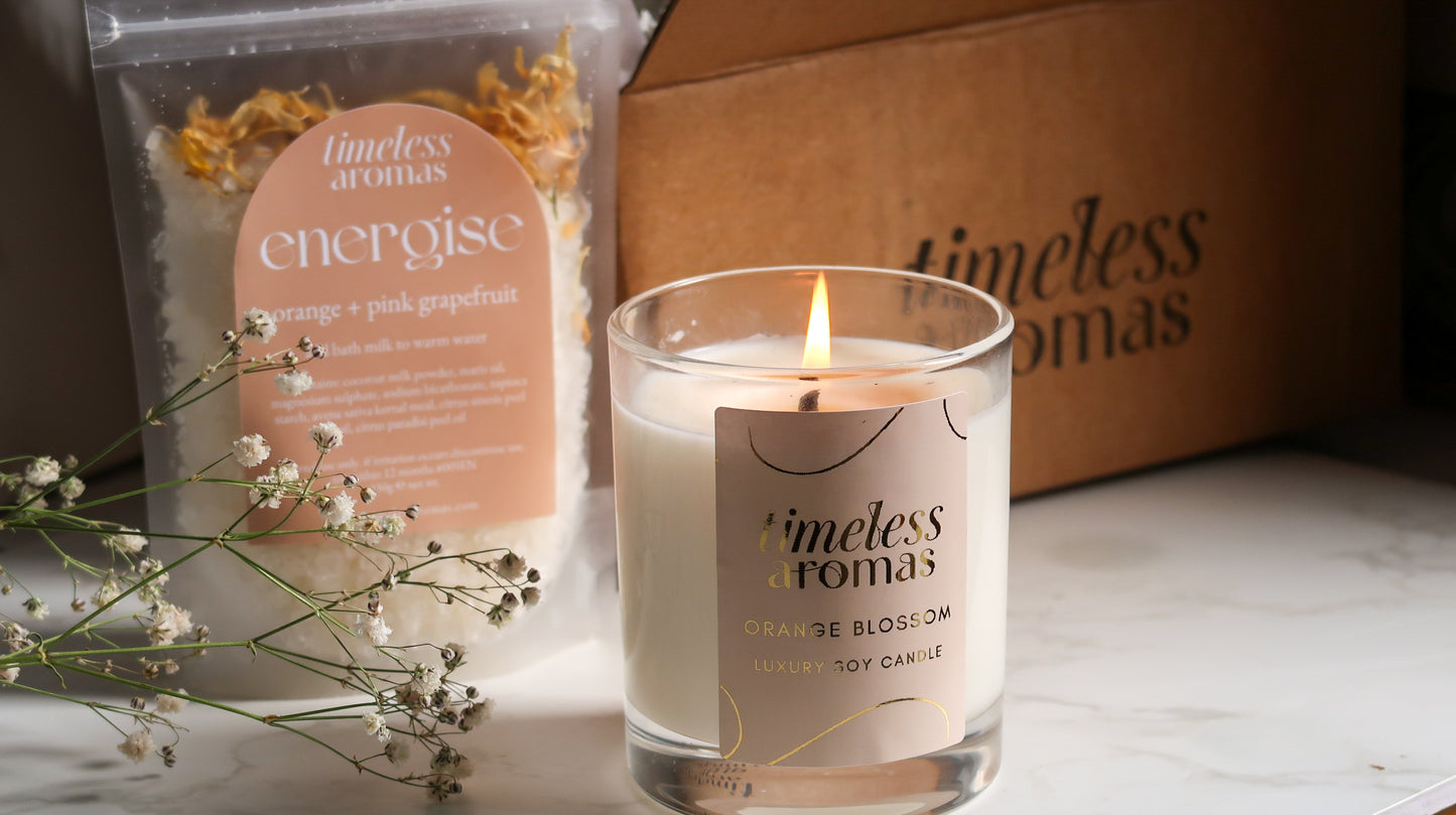 Close-up of Timeless Aromas Bloom and Energise Gift Set showcasing the candle and bath milk, representing an ideal home fragrance set with 200g of floral scents and refreshing orange vibes.
