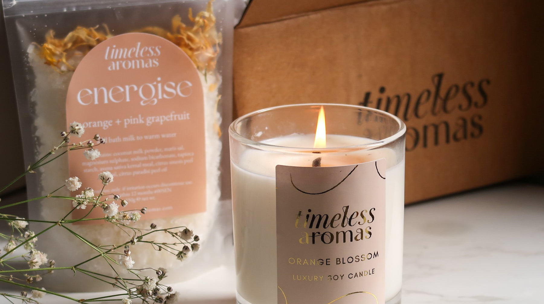 Close-up of Timeless Aromas Bloom and Energise Gift Set showcasing the candle and bath milk, representing an ideal home fragrance set with 200g of floral scents and refreshing orange vibes.